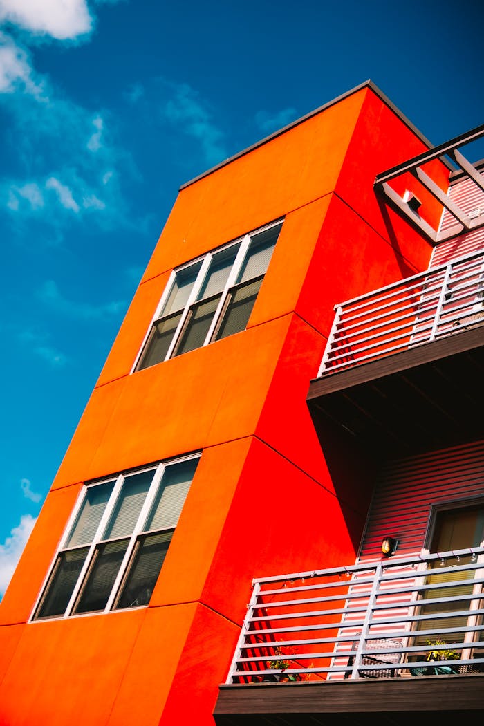 digital Low angle of a vibrant orange modern apartment building against a bright blue sky in Eau Claire.