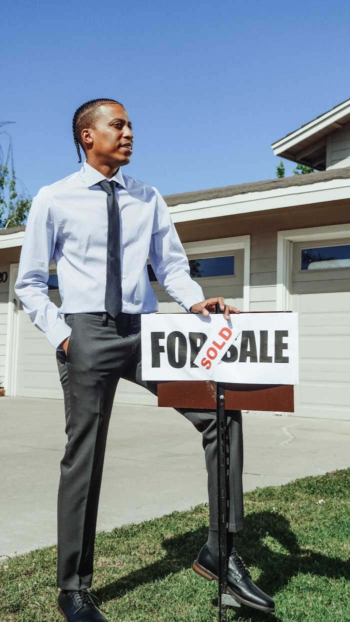 Realtor standing beside a sold sign in front of a new home.